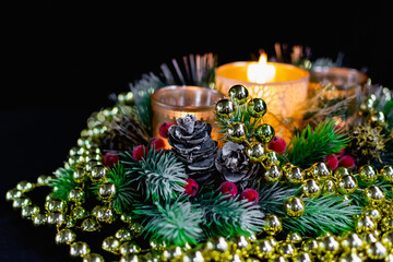 Christmas decorations on a black background by candlelight. Composition of Golden balls and beads, openwork candlesticks with patterns and branches of the Christmas tree. Elegant cones and red berries