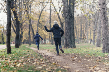 Fototapeta premium teen girl and boy running through the park and enjoys autumn, beautiful nature with yellow leaves