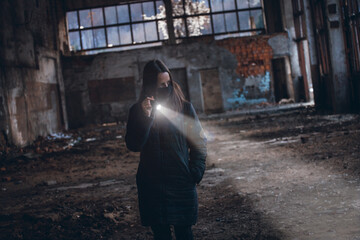 Lonely Girl with a Flashlight Walks in an Abandoned Room