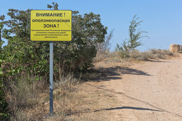 Sign with the inscription Attention! Landslide hazardous area! at the steep coast of the Black Sea on the North side of the city of Sevastopol, Crimea