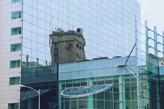 Reflejo del reloj del Studioul B1 TV sobre las ventanas del hotel Novotel de Bucarest, Rumanía. Imagen distorsionada de la calle sobre la superficie de cristal del moderno edificio del hotel.