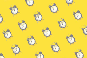 Pattern made of alarm clock on yellow background, top view