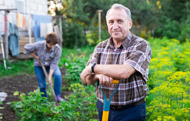 Naklejka na ściany i meble man farmer posing and digging in estate garden