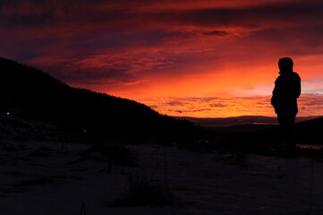 Obraz premium Black silhouette on mountain plateau during sunset with colorful red, violet, orange sky and clouds in winter in Scandinavia