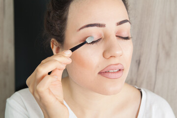 Fototapeta premium Young beautiful woman is wearing makeup. Fashion makeup and cosmetics. Woman's beautiful big eyes.