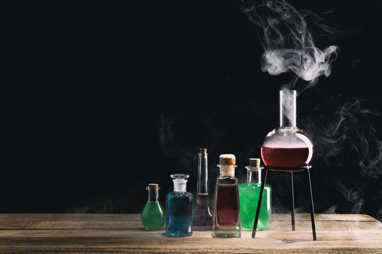Magic potion bottles on the wooden table. Witchcraft concept with potions. Magical still life with copy space on a dark background.