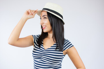 Naklejka premium Young beautiful woman wearing straw hat and striped t-shirt smiling over white background.