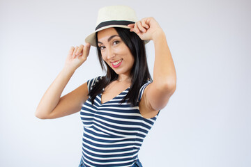 Young beautiful woman wearing straw hat and striped t-shirt smiling over white background.
