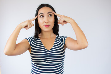 Young beautiful woman wearing striped t-shirt over white isolated background confuse and wondering about question. Uncertain with doubt, thinking with fingers on head. Pensive concept.