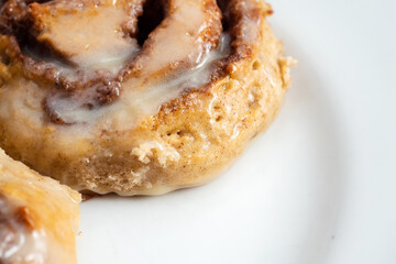 Hand made tasty cinnamon roll on a white plate. Pastry product. Close up shot.