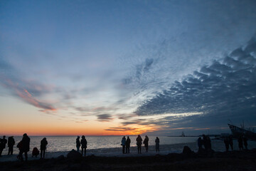 Sunset silhouettes of people on winter beach