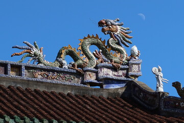 Fototapeta na wymiar Hoi An, Vietnam, November 21, 2020: Sculpture of a dragon on the roof of the Phap Bao Temple