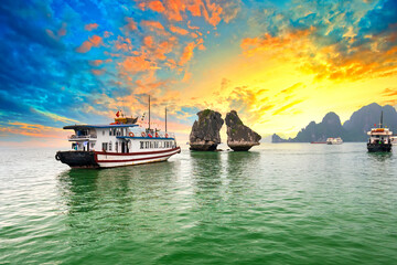 Dreamy sunset in Halong bay, Vietnam. Tourist cruise ship floating among limestone rocks. This is...