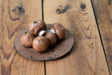 Champignon mushrooms in wooden plate on wooden background.