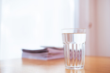 Purity drinking water in a drinking glass on the wooden table in office close up with copyspace. 