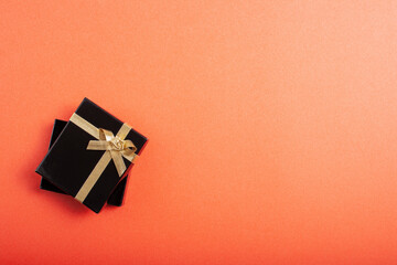 Black glossy box with a gift on a pink background. Horizontal orientation.