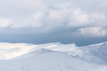 Snow-covered mountain range under a cloudy sky.