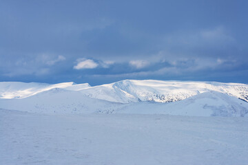 Snow-covered mountain range under a cloudy sky.