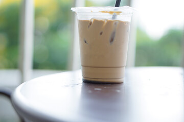 Iced coffee in a plastic cup with a straw that is still half a glass on the table