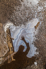 Silhouette of man reflected in dirty puddle