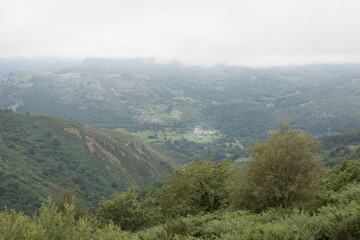 Landscape of hills covered in greenery and fog in Cantabria, Spain