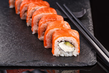 Beautiful Philadelphia rolls with salmon and cream cheese on a plate of black slate.