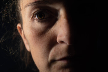 Obraz premium Close-up of a dark portrait of a very dimly lit woman. The woman is looking at infinity, transmitting a feeling of sadness or abandonment