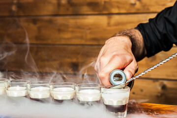 Bartender hands preparing steaming cocktail shots
