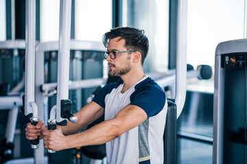 Fototapeta na wymiar Handsome man chest workouts in the gym.