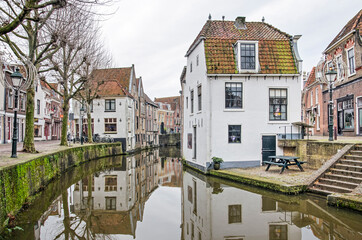 Fototapeta na wymiar Oudewater, The Netherlands, December 6, 2020: picturesque view from the cantral square towards historic houses reflecting in the mirror-like water of Lange Linschoten canal