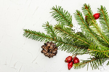 Naklejka na ściany i meble Christmas tree branches with pine cones and rosehip berries on white putty background