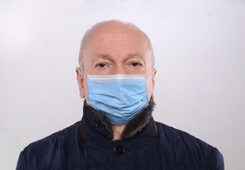 Senior man in medical protective mask posing in studio over gray background