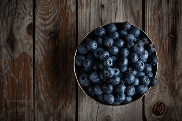 Bowl of fresh blueberries on rustic wooden table with copy space.