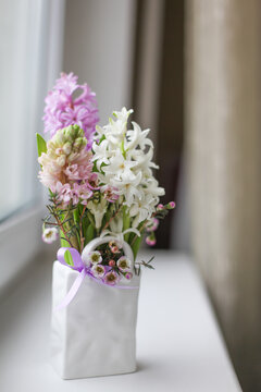 Beautiful white, pink and lilac hyacinths in a ceramic vase. Spring flowers composition on the window. Vertical image. Selective focus.