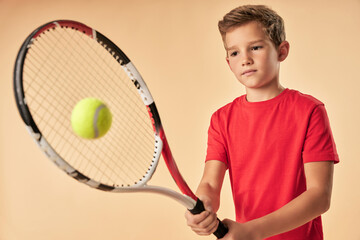 Adorable boy in red shirt playing tennis