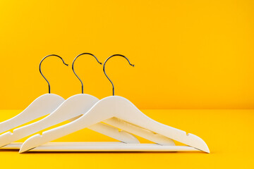 White hangers on a yellow background. Sales clothes concept.