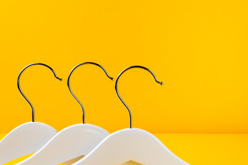 White hangers on a yellow background. Sales clothes concept.