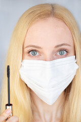 Girl in a mask with mascara. Make-up in a medical mask. Selective focus.