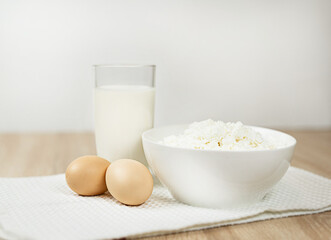 On the table a glass of milk, two eggs and cottage cheese
