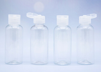 Transparent empty cosmetic bottles and jars on a soft blue background.