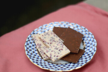 Vintage porcelain plate with pieces of dark and white chocolate. Selective focus.