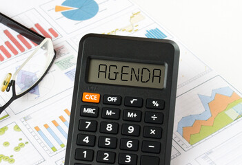 Calculator with text on the display Agenda it is on the financial charts with eyeglasses