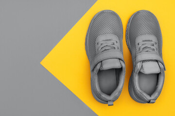Grey sport shoes on colorful background. New sneakers on grey and yellow pastel background.