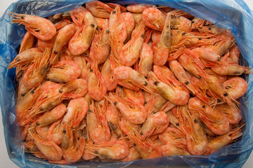 Frozen shrimp for food textures. Factory standard blue seafood packaging. View from above. Frozen shrimp background. Seafood.