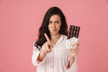 Displeased woman wagging her finger while posing with chocolate