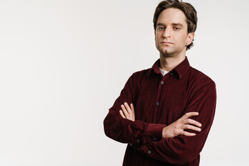 Handsome serious young man posing with arms crossed