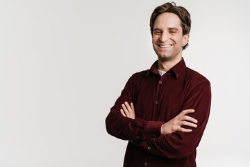 Handsome laughing young man posing with arms crossed