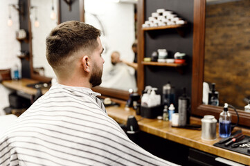 a client in a hairdressing salon changes his hairstyle during a haircut. stylish mens haircut.Beautiful mens hairstyle.barbershop.side and top view.the guy in the barber shop