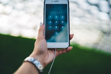 Cropped female blogger holding modern smartphone device open verification window for type protection password, selective focus on digital cellular technology with numbers on screen for safe using