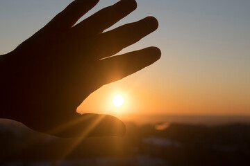 man's hand reaches out to the setting sun, the concept of hope, desire, dreams.. Conceptual design.